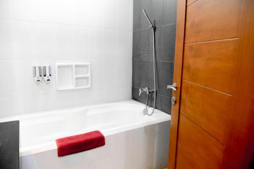 a bathroom with a shower with a red towel on the tub at Hotel Bonero Residence in Bojonegoro