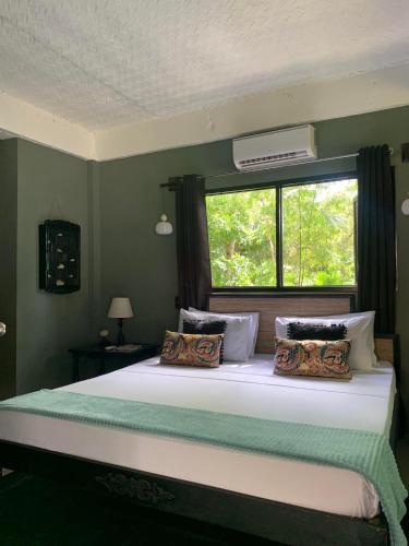a bedroom with a large bed with a window at La Plage Hotel in El Nido