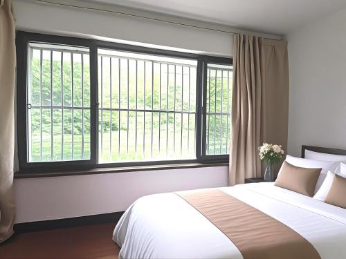 a bedroom with a large bed and a large window at Junyao Inn in Huangshan