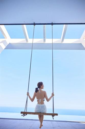 a woman in a bikini sitting on a swing at Dusit Thani Shuangyue Bay Resort Huizhou in Huidong