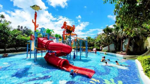a water park with a red slide in the water at Dusit Thani Shuangyue Bay Resort Huizhou in Huidong