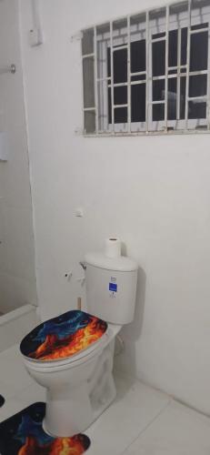 bagno bianco con servizi igienici e sedia colorata. di Holiday Rooms in Port Morant St Thomas Jamaica a Port Morant
