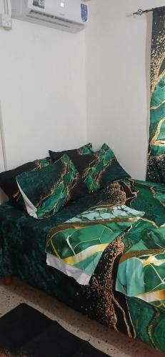 a bed with a green comforter and pillows at Holiday Rooms St Thomas Jamaica full air-con in Port Morant