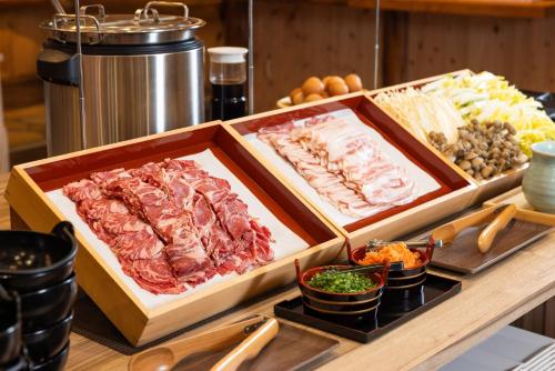 a buffet with meats and other food on a table at Aso Baien Spa Resort in Minami Aso