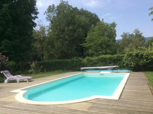 - une piscine avec une table et une chaise à côté dans l'établissement Domaine du Valromey, à Champagne-en-Valromey