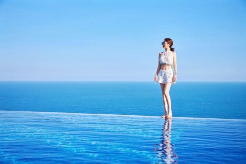 a woman standing on the edge of a body of water at Dusit Thani Shuangyue Bay Resort Huizhou in Huidong