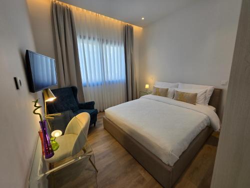 a bedroom with a bed and a chair and a television at TG NEW Luxury Private Resort & SPA Villas - Heated Salty Swimming Pool, Outdoor Jacuzzi, Sauna, Exotic Garden in Limassol