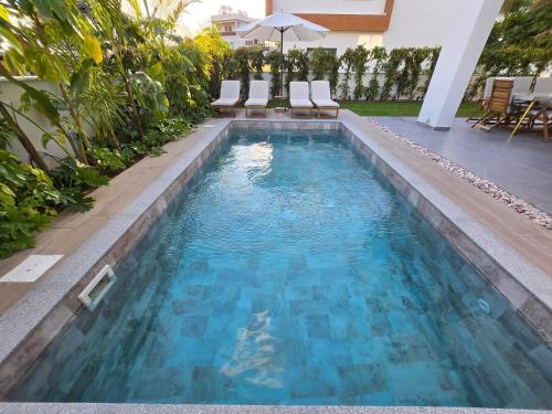 an infinity pool with blue water in a backyard at TG NEW Luxury Private Resort & SPA Villas - Heated Salty Swimming Pool, Outdoor Jacuzzi, Sauna, Exotic Garden in Limassol