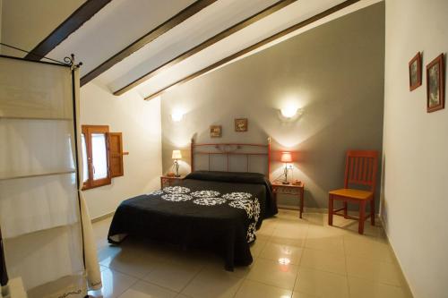 a bedroom with a bed and two tables and a chair at Complejo Rural La Belluga in Segorbe