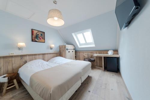 a bedroom with a bed and a table and a television at Hotel Giethoorn in Giethoorn