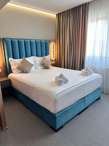 a bedroom with a large bed with a blue headboard at River Park Hotel in Drăgăşani