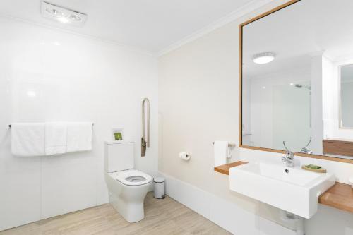 a white bathroom with a toilet and a sink at Nu Leaf Retreat in Pokolbin