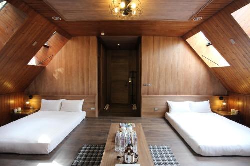 two beds in a room with wooden walls and ceilings at Taichung Business Hotel - Immortals Hills in Heping