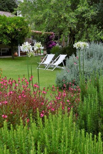 two lawn chairs sitting in a garden with flowers at Giallo Limone in Teulada