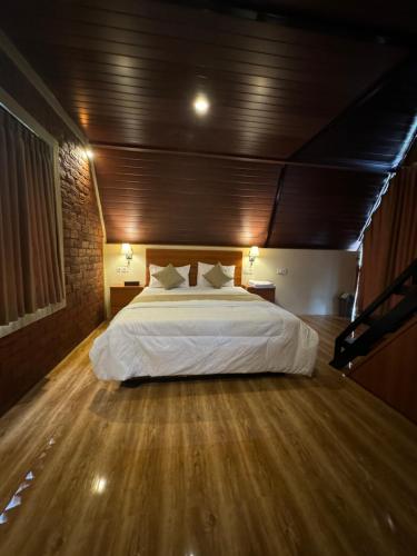 a bedroom with a large bed and a wooden floor at Lombok Hidden Villa in Tetebatu