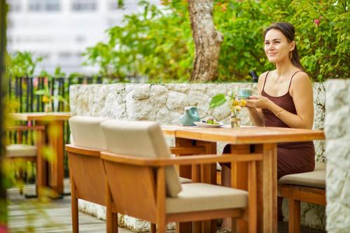 Eine Frau, die mit einem Glas Wein am Tisch sitzt. in der Unterkunft Aahana Village Bali in Canggu