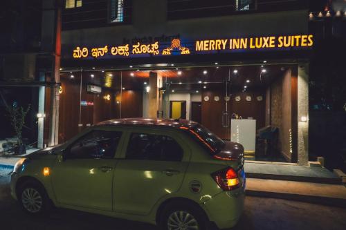 バンガロールにあるMerry Inn Luxe Suites near Kempegowda international airportの店前に停車する小型緑車