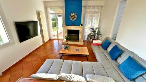 un salon avec un canapé et une cheminée dans l'établissement La Villa du Thym, Spacieuse villa familiale, piscine et vue dégagée, à Saint-Gély-du-Fesc