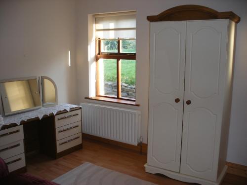 Schlafzimmer mit einem weißen Schrank und einem Spiegel in der Unterkunft Mountshannon cottage in Mountshannon