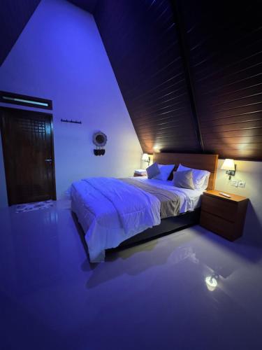 a bedroom with a large bed with blue lighting at Lombok Hidden Villa in Tetebatu