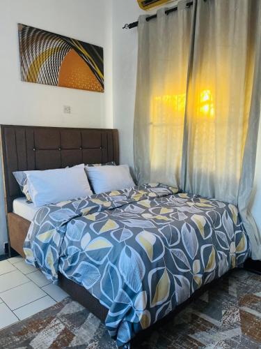 a bedroom with a bed with a blue and yellow comforter at Nadi Homes in Dar es Salaam