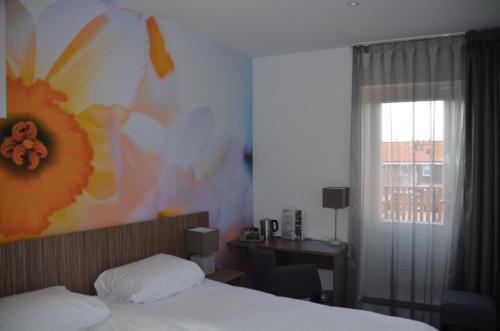 a bedroom with a bed and a desk and a window at Hotel Restaurant de Engel in Lisse