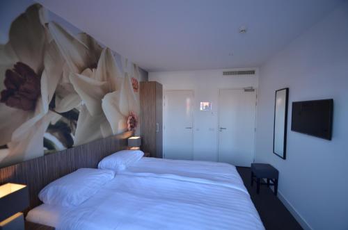 a bedroom with a bed with a painting on the wall at Hotel Restaurant de Engel in Lisse