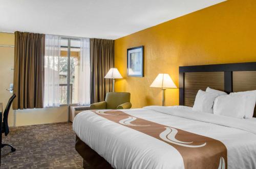 a hotel room with a large bed and a chair at Quality Inn University Area in Troy