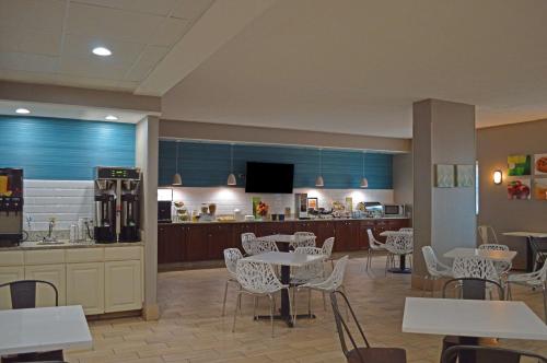 a restaurant with tables and chairs and a kitchen at Country Inn & Suites by Radisson Rehoboth Beach - Dewey in Rehoboth Beach