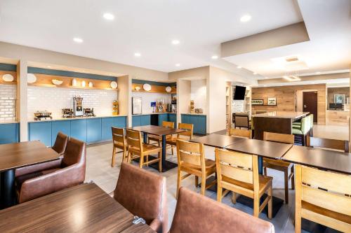 a restaurant with tables and chairs and a kitchen at Country Inn & Suites by Radisson, LSU - Medical Corridor in Baton Rouge
