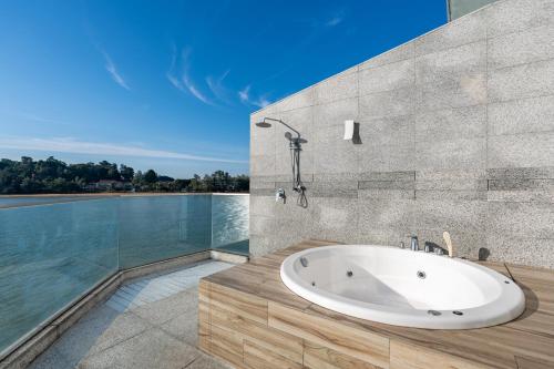 a bath tub in a bathroom with a view of the water at Lexis Hibiscus Port Dickson in Port Dickson