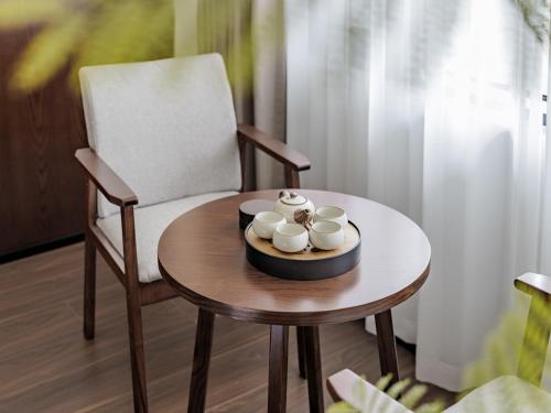 a table with a chair and mugs on it at ZhangJiaJie Enjoy Nature hotel in Hanqiyu