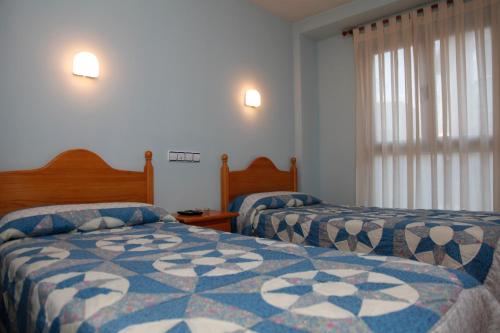 a bedroom with two beds and a window at Hostal La Granja in Yunquera de Henares