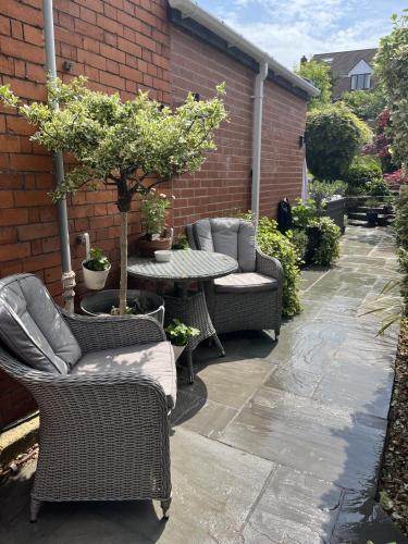 a patio with wicker chairs and a table with a tree at The Glastonbury Townhouse B&B in Glastonbury