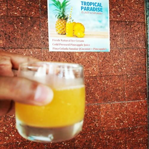 a person holding a glass of pineapple juice at The big pineapple estate suites in Udupi