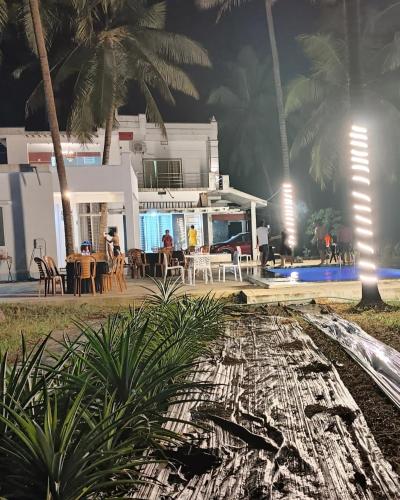 a villa with a swimming pool at night at The big pineapple estate suites in Udupi
