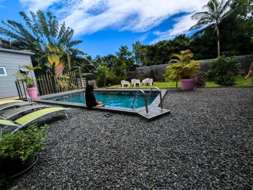 a woman sitting on a bench next to a swimming pool at Leu Zarlor Location in Piton Saint-Leu