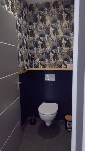 La salle de bains est pourvue de toilettes et d'un mur noir et blanc. dans l'établissement Gite de saint Antoine, à Ploudiry