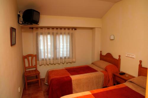 ein Hotelzimmer mit 2 Betten und einem TV in der Unterkunft Hostal La Granja in Yunquera de Henares