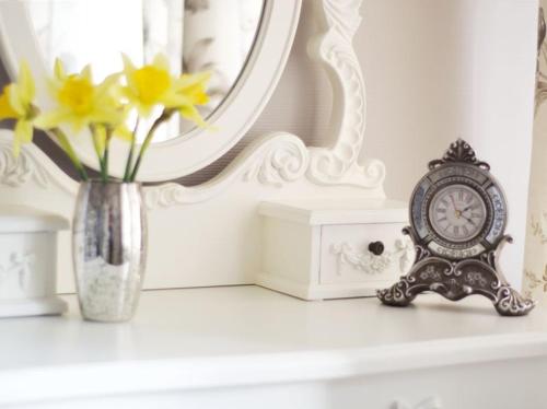 a vase of flowers and a clock sitting on a mantle at The Cambridge Guest House by Tas in Cambridge
