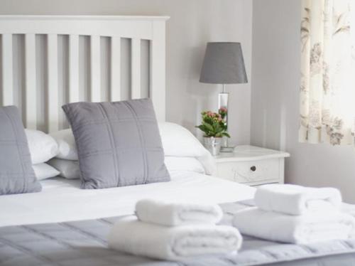 a white bedroom with a bed with towels on it at The Cambridge Guest House by Tas in Cambridge