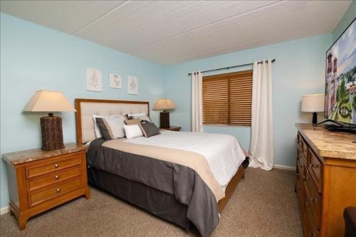 a bedroom with a bed and a dresser and a television at Mystic Sands I Steps to Beach I Free activities condo in Saint Augustine Beach