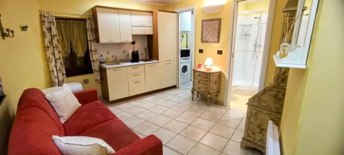 un salon avec un canapé rouge et une cuisine dans l'établissement Studio Vieux Village Roquebrune Cap Martin RCM, à Roquebrune-Cap-Martin