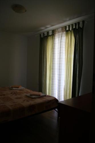 a bedroom with a bed and a window with curtains at Apartmani Sara in Vlašići
