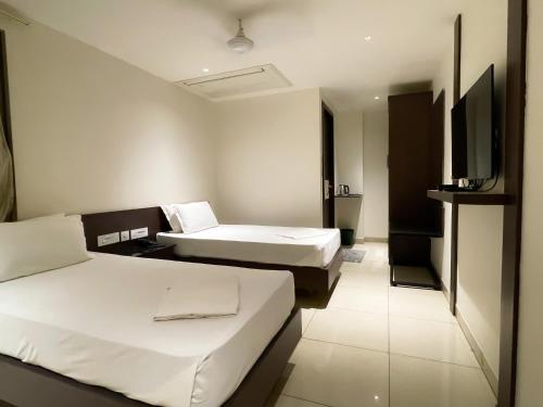 a hotel room with two beds and a flat screen tv at SV Grand in Mettuppālaiyam