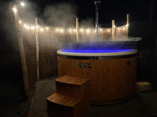a wooden bath tub with blue lighting in the dark at Sallands natuurhuisje Hellendoorn hottub Metz in Haarle