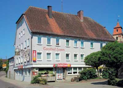 duży biały budynek z brązowym dachem w obiekcie Hotel-Gasthof Lamm w mieście Rot am See