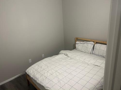 a bedroom with a bed with white sheets and pillows at Basement Suite Near Edmonton Airport YEG in Edmonton