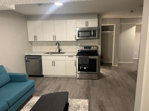 a kitchen with white cabinets and a blue couch at Basement Suite Near Edmonton Airport YEG in Edmonton