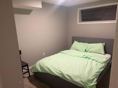 a bedroom with a bed with green sheets and a window at Basement Suite Near Edmonton Airport YEG in Edmonton